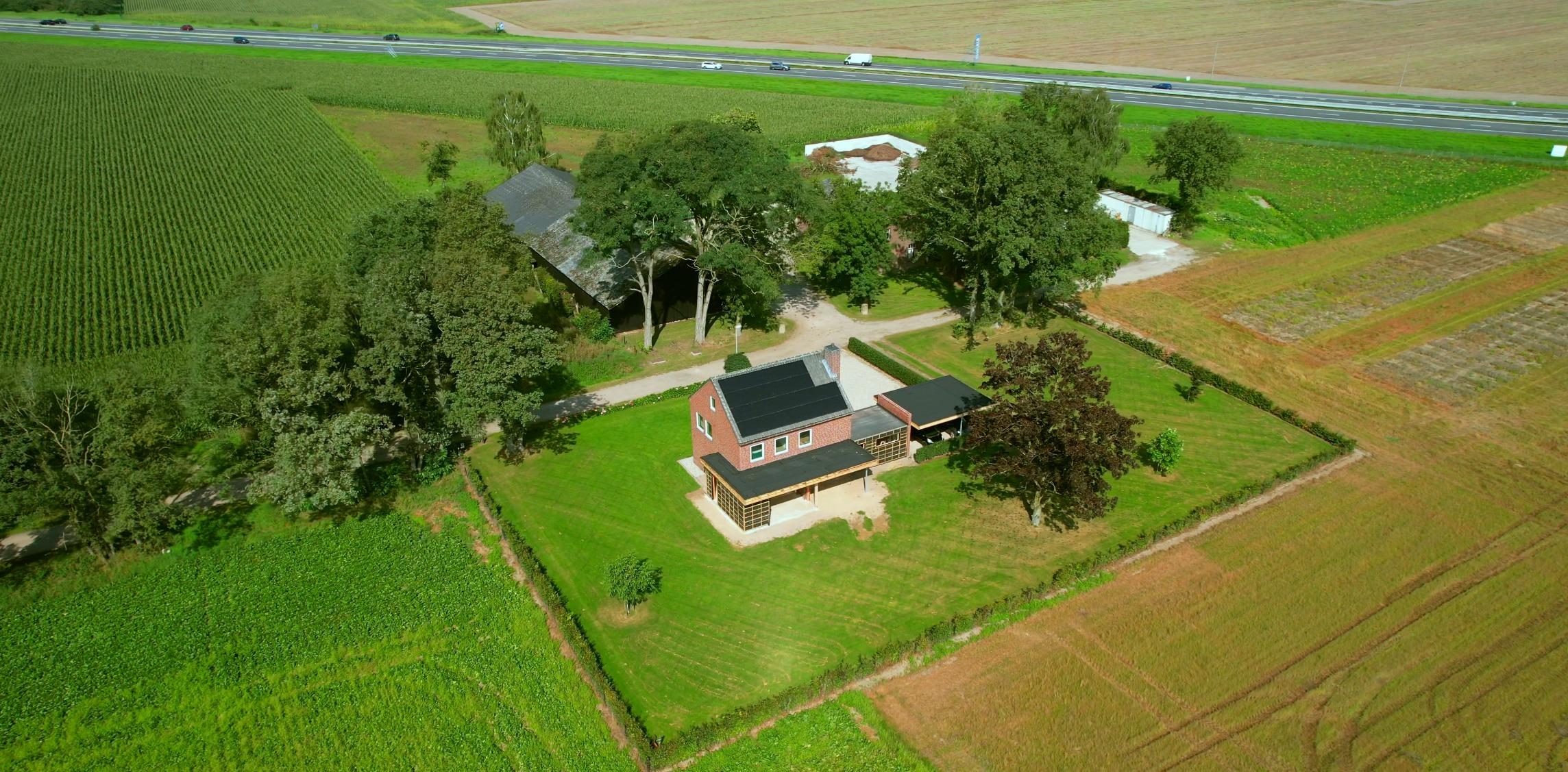 Luchtfoto van de verbouwde bedrijfswoning met zonnepanelen en tuin