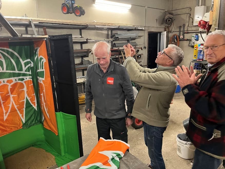 Drie mannen in de werkplaats met oranje-groene vlaggen