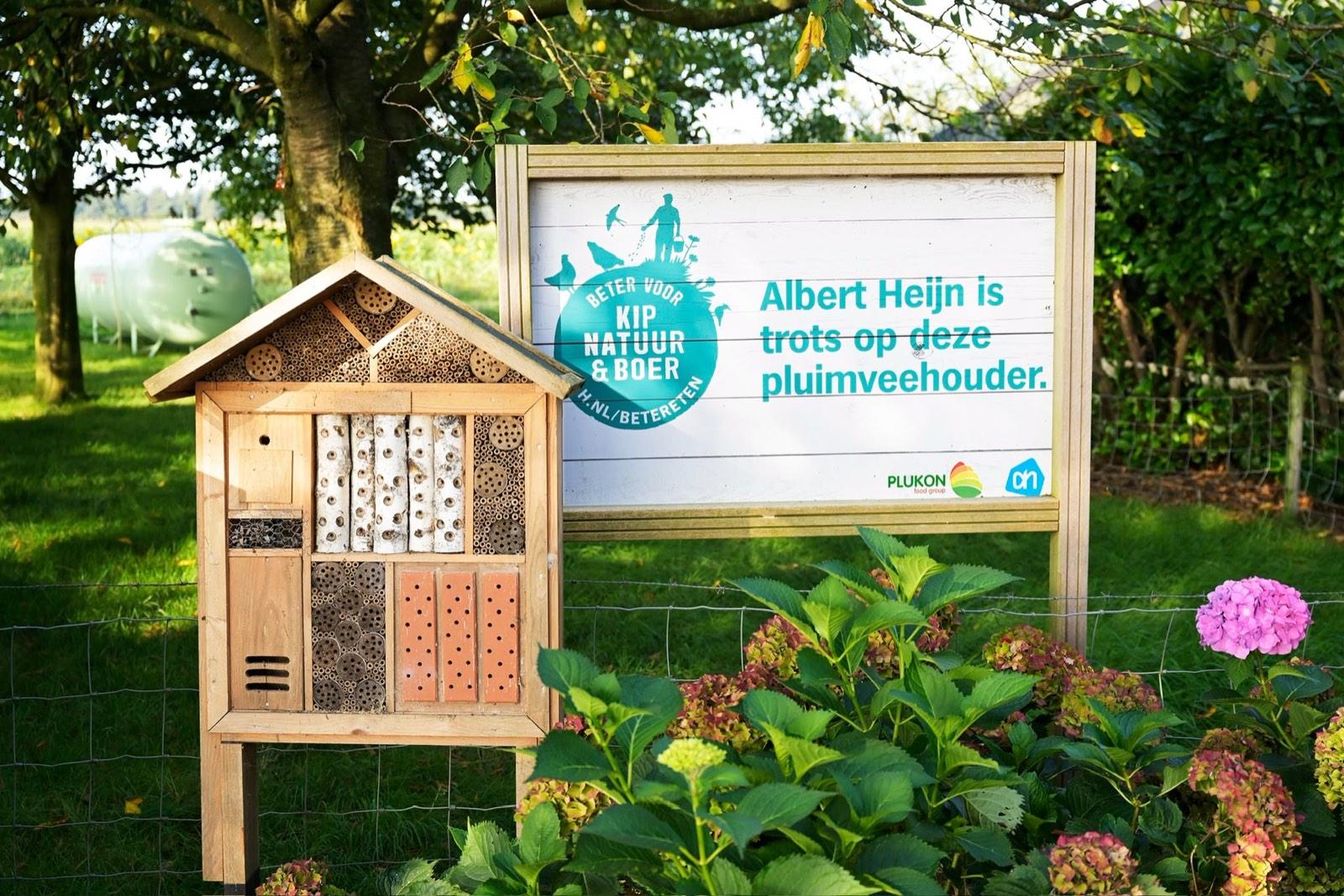 Houten insectenhotel naast het bord Beter voor Kip, Natuur & Boer van Albert Heijn, met hortensia's ervoor