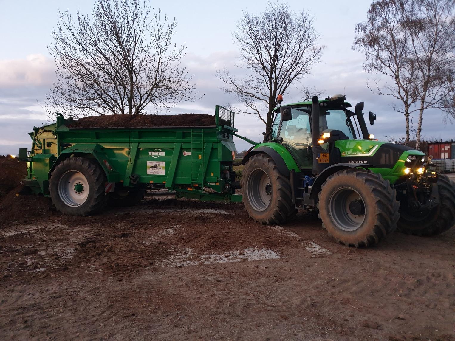 Groene Deutz-trekker met volle mestverspreider in de schemer