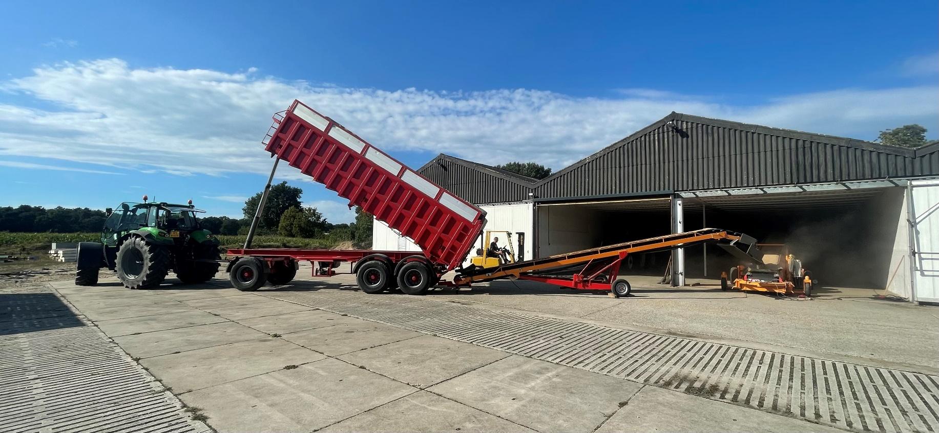 Rode kipper lost aardappelen via de transportband de bewaarloods in